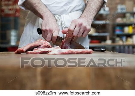 Picture - Butcher preparing pork ribs. Fotosearch