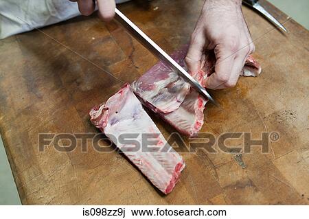 Stock Image - Butcher preparing pork ribs. Fotosearch