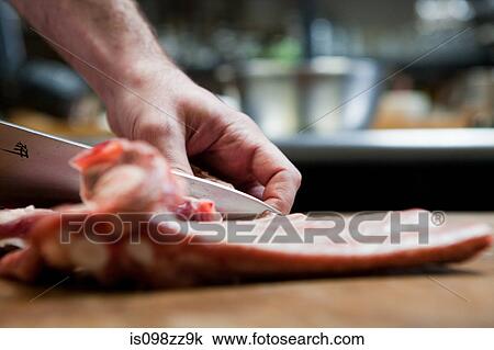 Stock Image - Butcher preparing pork ribs. Fotosearch
