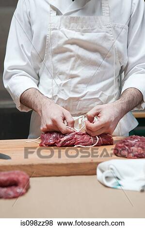 Butcher tying beef tenderloin with string View Large Photo Image Stock Photo - Butcher tying beef tenderloin with string. Fotosearch