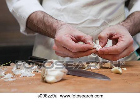 Stock Photograph - Chef adding peeling garlic. Fotosearch