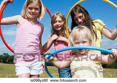 Stock Image - Four girls with plastic hoops, portrait. Fotosearch