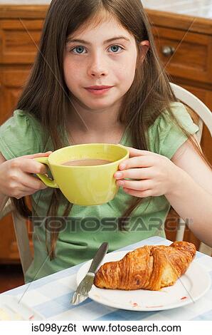 Stock Photograph - Girl drinking hot chocolate with croissant. Fotosearch