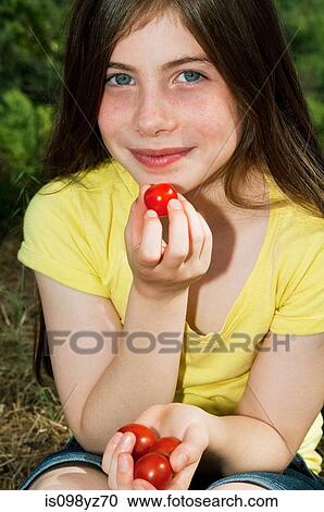 Stock Image - Girl eating cherry tomatoes. Fotosearch