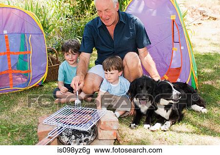Stock Image - Grandfather and grandsons having barbecue. Fotosearch