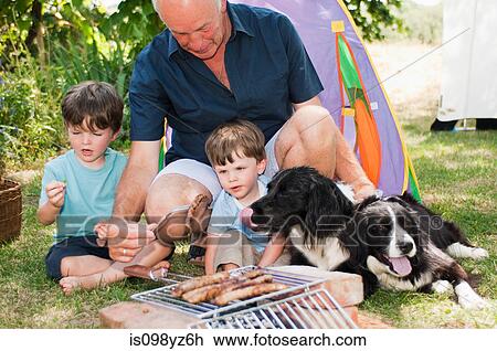 Stock Image - Grandfather and grandsons having barbecue. Fotosearch