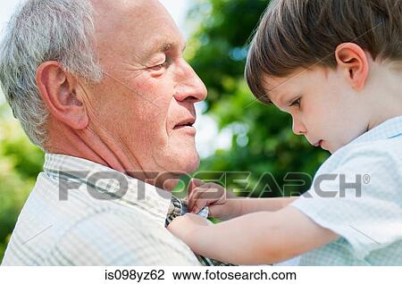 Stock Image - Grandfather holding grandson, close up. Fotosearch
