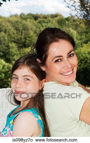Picture - Mother and daughter back to back, portrait. Fotosearch