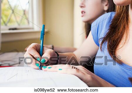 Stock Image - Teenage girsl doing homework. Fotosearch