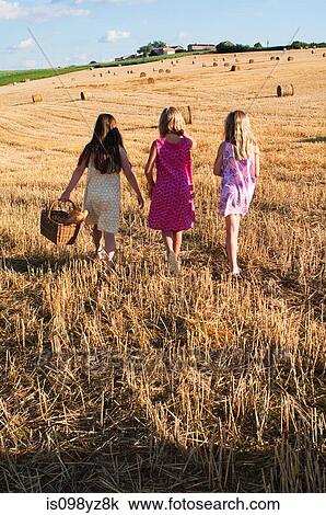 Stock Image - Three girls walking in field. Fotosearch