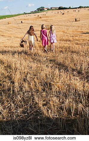 Stock Image - Three girls walking in field. Fotosearch