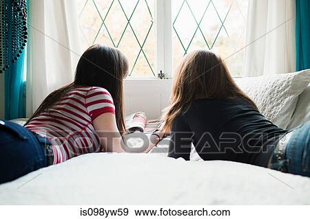 Two teenage girls lying on bed View Large Photo Image Stock Photo - Two teenage girls lying on bed. Fotosearch
