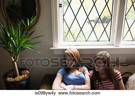Two teenage girls sitting by window View Large Photo Image Stock Photo - Two teenage girls sitting by window. Fotosearch