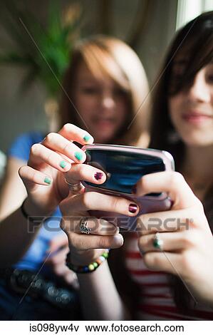 Two teenage girls using smartphone View Large Photo Image Stock Photo - Two teenage girls using smartphone. Fotosearch