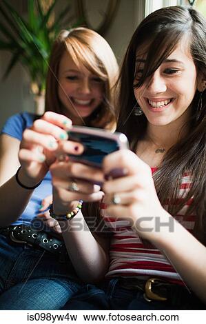 Two teenage girls using smartphone View Large Photo Image Stock Photo - Two teenage girls using smartphone. Fotosearch