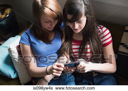 Two teenage girls using smartphone View Large Photo Image Stock Photo - Two teenage girls using smartphone. Fotosearch