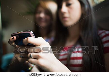 Stock Photograph - Two teenage girls using smartphone. Fotosearch