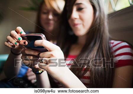 Stock Photograph - Two teenage girls using smartphone. Fotosearch