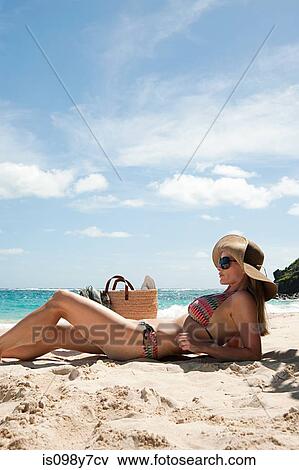 Stock Photo - Woman lying on sandy beach, Mustique, Grenadine Islands. Fotosearch