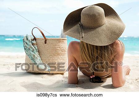 Stock Photograph - Woman lying on sandy beach, Mustique, Grenadine Islands. Fotosearch