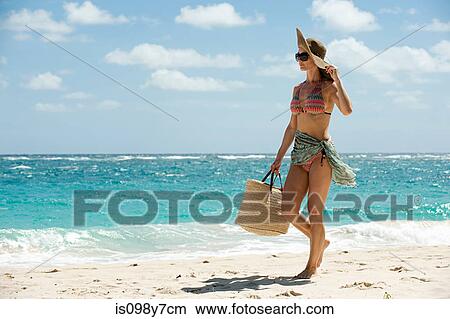 Picture - Woman walking on sandy beach, Mustique, Grenadine Islands. Fotosearch