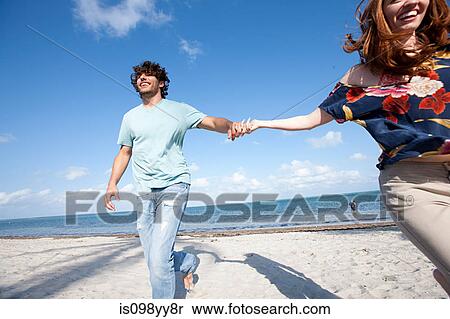 Stock Photography - Young couple holding hands on beach. Fotosearch