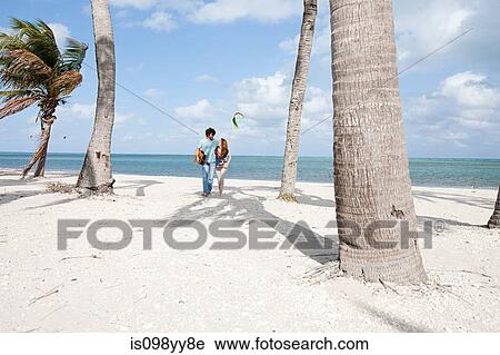 Stock Image - Young couple walking on beach. Fotosearch