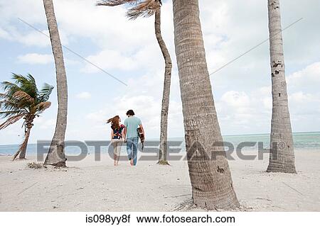 Stock Image - Young couple walking on beach. Fotosearch