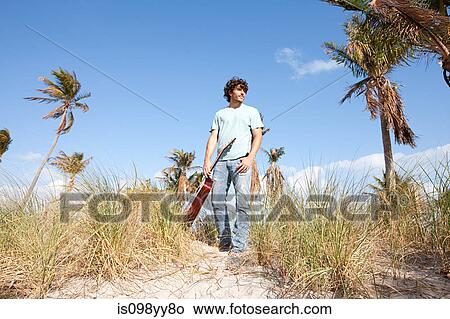 Young man holding guitar on beach View Large Photo Image Picture - Young man holding guitar on beach. Fotosearch