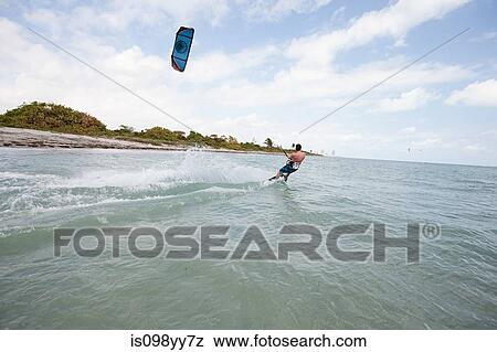 Stock Photo - Young man kitesurfing. Fotosearch