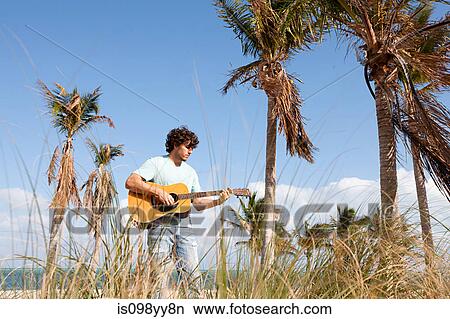 Young man playing guitar on beach View Large Photo Image Picture - Young man playing guitar on beach. Fotosearch