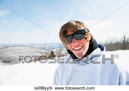 Stock Image - Young man wearing sunglasses and hooded top, portrait. Fotosearch