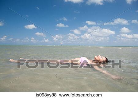 Stock Photo - Young woman floating in sea. Fotosearch