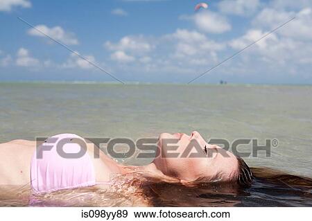 Stock Photo - Young woman floating in sea. Fotosearch