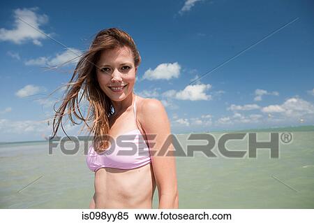 Stock Photography - Young woman in sea looking at camera, portrait. Fotosearch