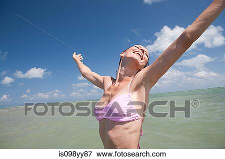 Young woman in sea with arms out, portrait View Large Photo Image Stock Photo - Young woman in sea with arms out, portrait. Fotosearch