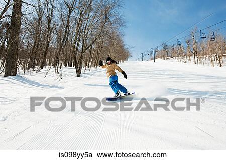 Stock Image - Young woman snowboarding. Fotosearch