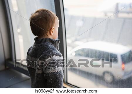 Stock Image - Boy looking through airport window. Fotosearch