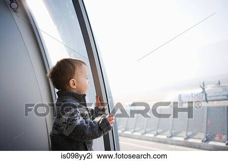 Stock Image - Boy looking through airport window. Fotosearch