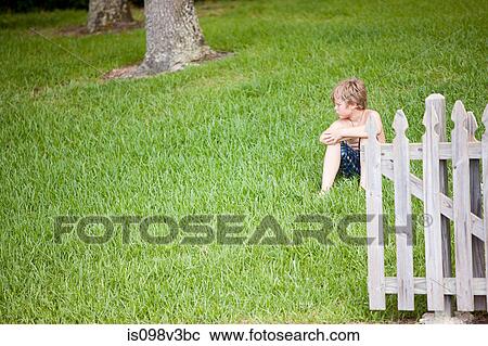 Stock Image - Boy sitting on green grass. Fotosearch