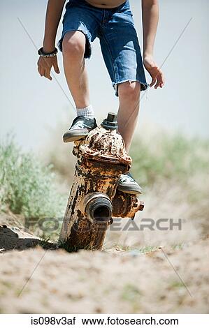 Stock Image - Boy standing on top of fire hydrant. Fotosearch