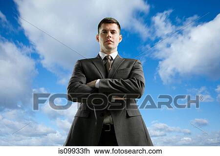 Stock Image - Businessman with crossed arms, low angle. Fotosearch