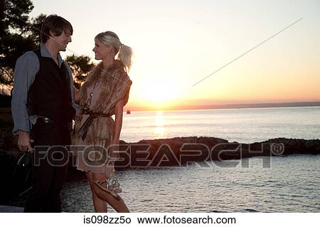Picture - Couple by the sea at sunset. Fotosearch