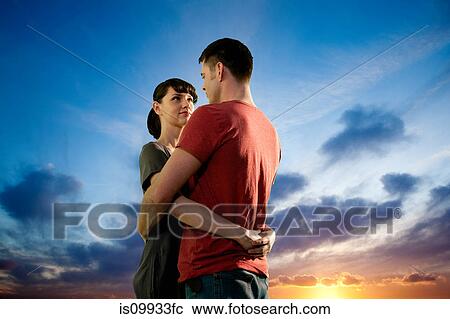 Couple embracing against dramatic sunset View Large Photo Image Stock Image - Couple embracing against dramatic sunset. Fotosearch