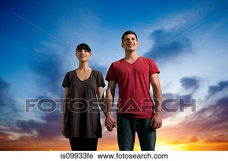 Couple holding hands against dramatic sunset View Large Photo Image Stock Image - Couple holding hands against dramatic sunset. Fotosearch