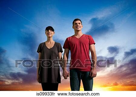 Couple holding hands against dramatic sunset View Large Photo Image Stock Photography - Couple holding hands against dramatic sunset. Fotosearch