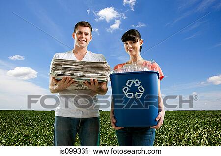 Couple in field holding recycling bin and pile of newspapers View Large Photo Image Stock Image - Couple in field holding recycling bin and pile of newspapers. Fotosearch