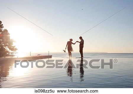 Stock Photograph - Couple in the ocean at sunset. Fotosearch