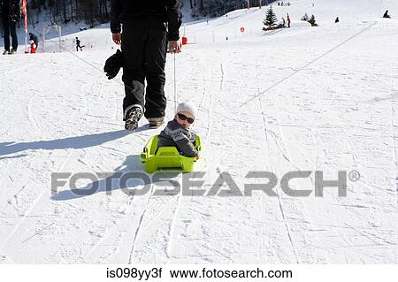 Stock Image - Father pulling son on sledge. Fotosearch