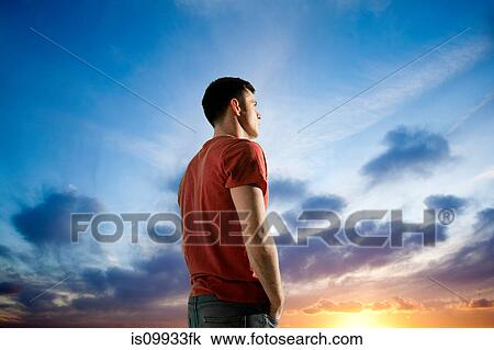 Man against dramatic sunset, looking away View Large Photo Image Stock Image - Man against dramatic sunset, looking away. Fotosearch